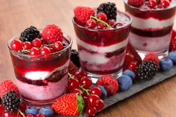 close up of layered dessert with red fruits on wooden background