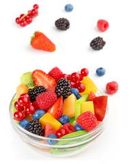 portion of vibrant fruit salad and scattered fruits on white background