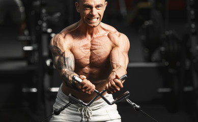 Fototapeta na wymiar Strong bodybuilder doing exercise in the gym