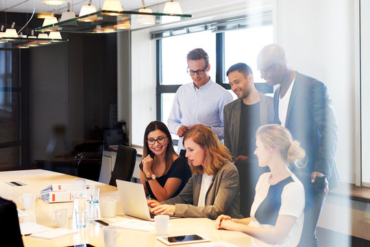 Group of executives gathered around laptop