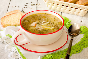 Rice soup with chicken in a ceramic bowl on white wooden background