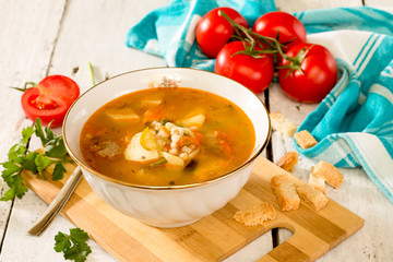Solyanka, meat and pickle soup on in a white ceramic bowl on a white wooden background. Traditional Russian and Ukranian soup