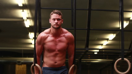 Fit man using gymnastics rings at crossfit gym