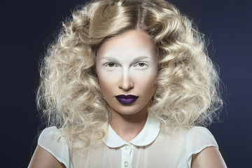 Art photo of beautiful girl with violet lips and pale eyes. Picture taken in the studio on a blue background.