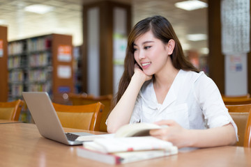 Fototapeta premium Asian beautiful female student study in library with laptop
