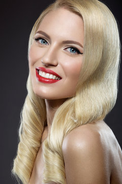 Beautiful blonde in a Hollywood manner with curls, red lips. Beauty face. Picture taken in the studio