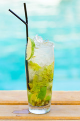 Mohito mojito drink with ice mint and lime near swimming pool