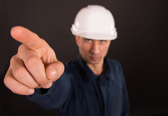 Portrait of a builder pointing away, dark background