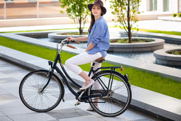 Pretty girl in hat riding a bicycle at street