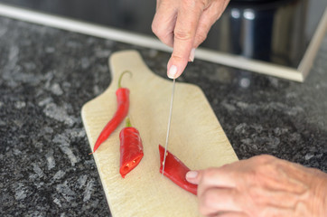 Ältere Frau schneidet Chilli