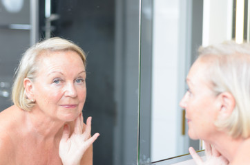Seniorin blickt in den Spiegel