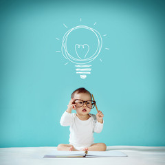Concept, idea of happy little baby with bulb at blackboard, new
