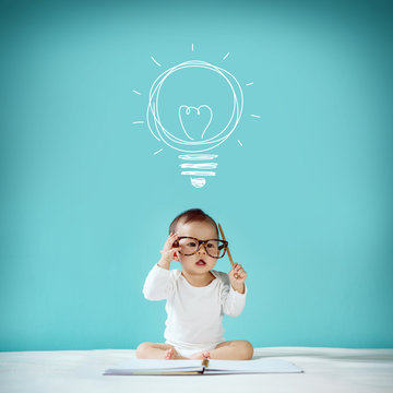 Concept, idea of happy little baby with bulb at blackboard, new