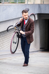 Fototapeta na wymiar Handsome businessman carrying his bicycle