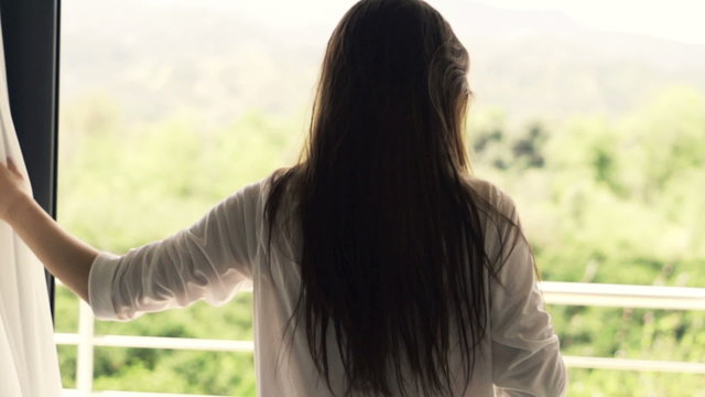 Young woman unveil curtain and walking out on terrace, slow motion shot at 240fps
