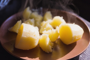 Hot boiled potatoes on the plate, back light