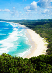 Byron Bay Tallow Beach under a blue sky with fluffy white clouds