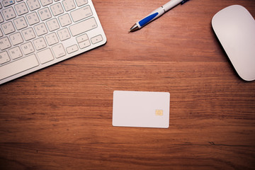 Blank credit card on office table with keyboard, mouse and pen.