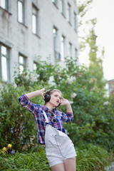 Naklejka premium Hipster girl dancing to music in headphones.