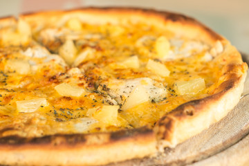 Baked cut pizza with pineapple and meat on wooden board