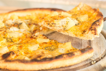 Baked cut pizza with pineapple and meat on wooden board