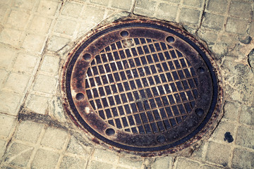 Round rusted hatch in urban pavement