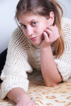 Cute blonde wearing knitted woolen pullover. House wall as background