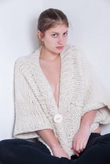 Cute blonde wearing knitted woolen pullover. House wall as background