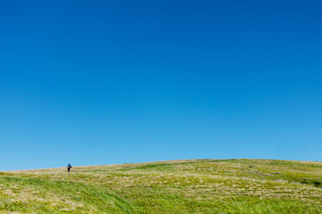Hiker on the green plain under blue skies