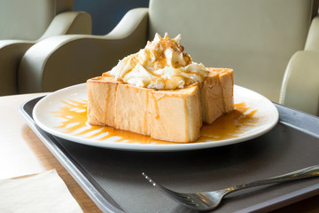Golden honey toast in the white dish with whipped cream on top
