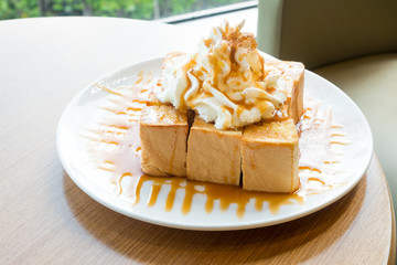Golden honey toast in the white dish with whipped cream on top