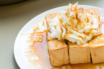 Golden honey toast in the white dish with whipped cream on top