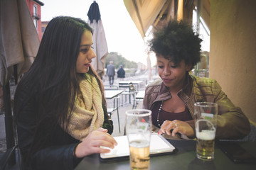 two multiethnic beautiful young woman black and caucasian using