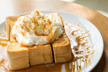 Golden honey toast in the white dish with whipped cream on top