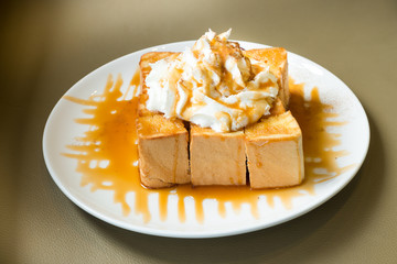 Golden honey toast in the white dish with whipped cream on top