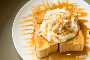 Golden honey toast in the white dish with whipped cream on top