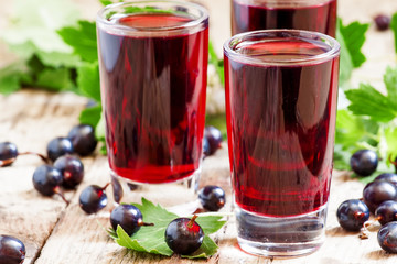 Fresh black currant juice with berries in glasses on an old wood