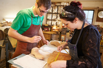 Two young shoemakers preparing shoe lasts in a workshop