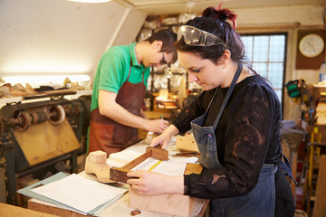 Two young shoemakers preparing shoe lasts in a workshop