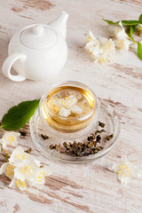 Obraz na płótnie Canvas Glass cup of green tea with jasmine on wooden background