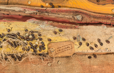 Chicchi di caffè crudo e torrefatto sparsi su un piano di legno grezzo colorato.Tela sacco di juta.