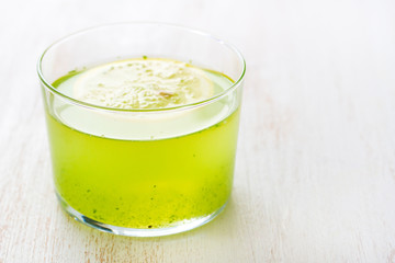 healthy drink with lemon in glass on white wooden background