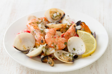 seafood salad on plate on white wooden background