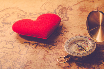 Valentine day background. Old compass on vintage map with red heart. Retro filter. Direction to real love of your heart concept.