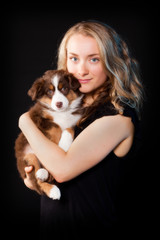 Portait of a young pretty woman with her puppy on a black backgr