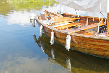 Old wooden sail boat reflecting in the water
