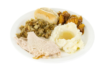 Turkey Dinner – A plate of sliced turkey, mashed potatoes and gravy, stuffing, candied yams, and a roll. Isolated on white background with clipping path. © Cathleen