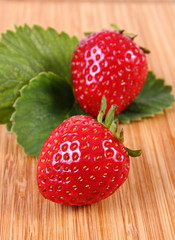 Strawberry with leaves on wooden surface