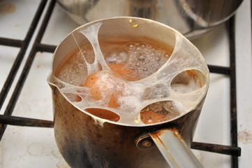 Saucepan with boiling eggs, apparently cracked, ugly but still on a kitchen stove
