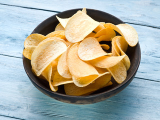 Potato chips on a wooden background.